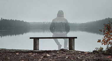 Personne assise sur un banc en avant d'un lac en automne