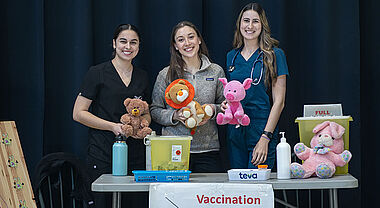 Trois bénévoles devant leur kiosque sur la vaccination