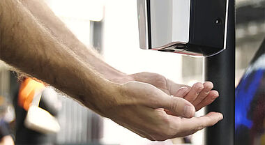 Deux mains sous le distributeur d'un produit désinfectant